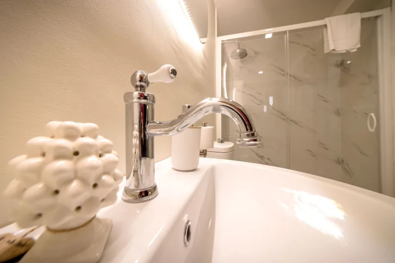 Bathroom with marble-look shower and chrome tap