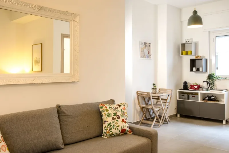 Living room with grey sofa, mirror and kitchenette