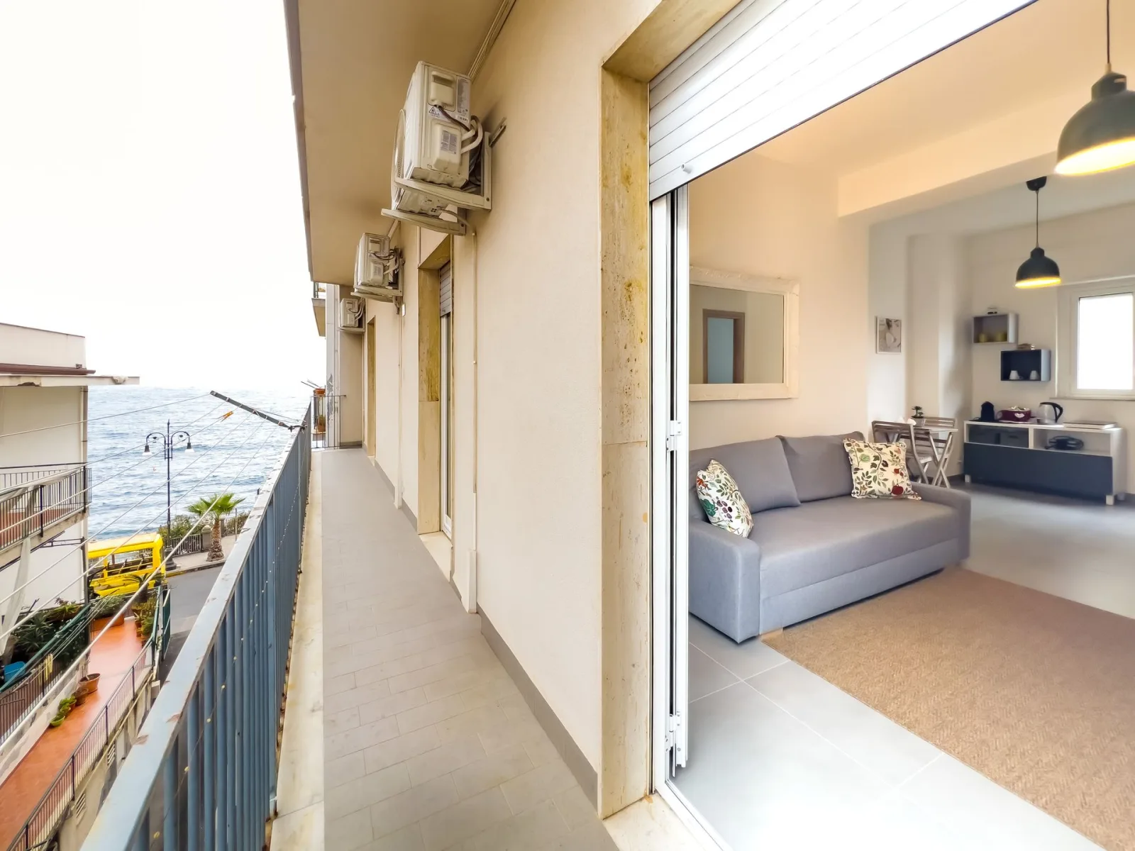 A balcony with a sea view beside the living room of a seafront flat in Aci Castello