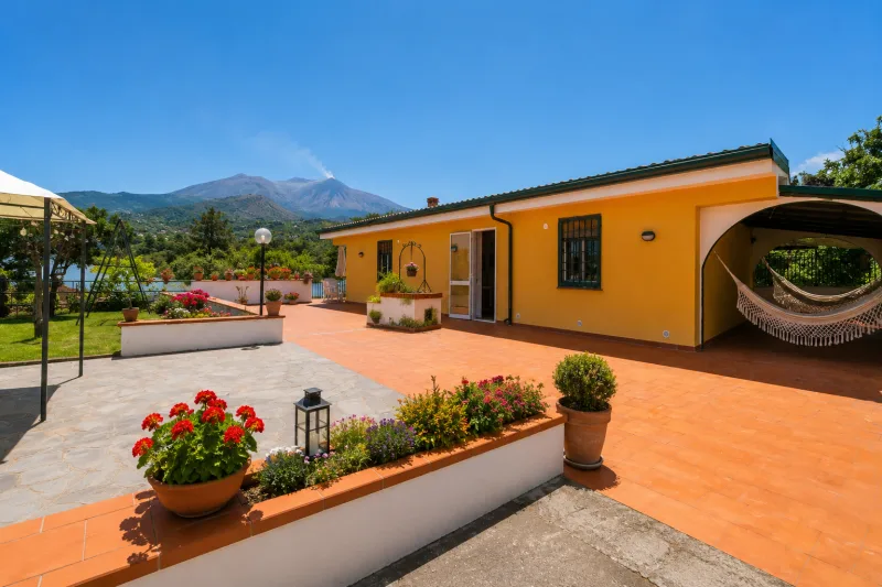 Yellow single-storey house and terrace with Etna in view