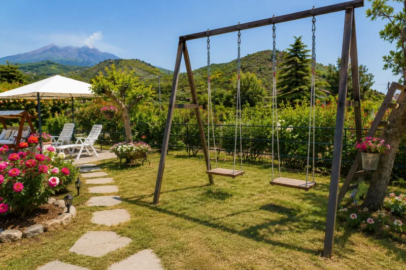 Garden lawn with swings and Etna in the distance