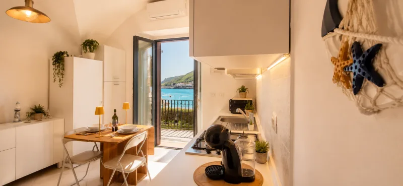 Open-plan kitchen and dining area with balcony door to the sea