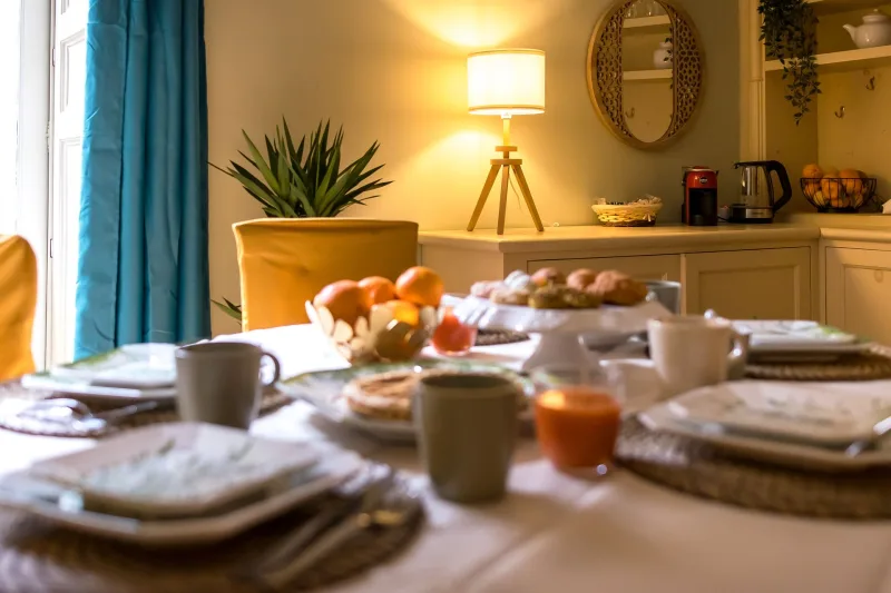 A breakfast table laid with fruit and pastries by the window of a Catania apartment