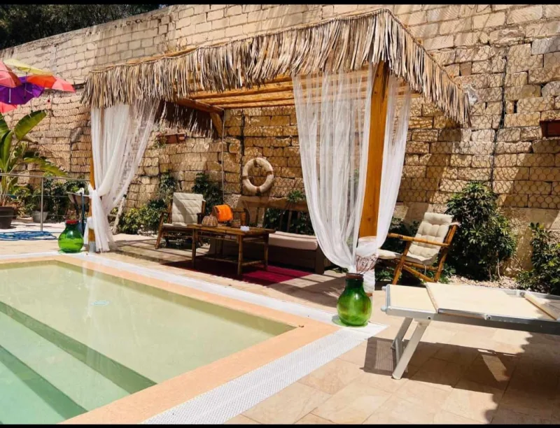 Thatched poolside cabana with white curtains