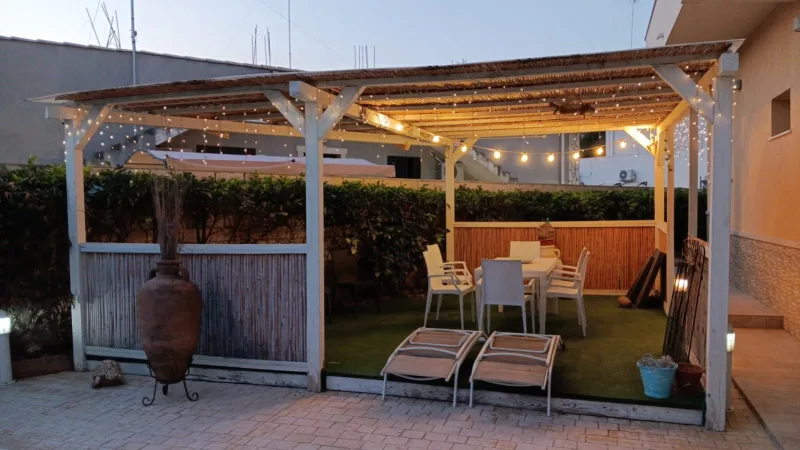 Lit pergola and loungers at dusk